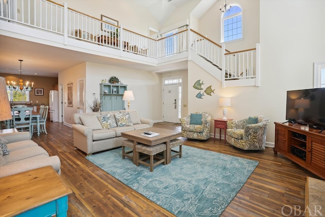 living room featuring dark wood finished floors, plenty of natural light, baseboards, and an inviting chandelier