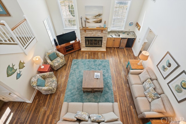 living area featuring stairs, a fireplace, wood finished floors, and a wealth of natural light