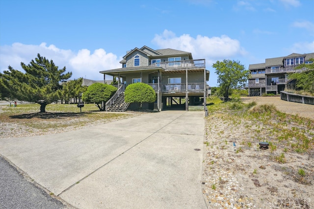 view of front of property featuring driveway, stairway, a porch, and a carport