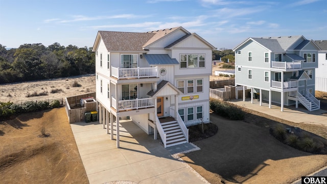 rear view of property featuring a shingled roof, stairway, and a balcony