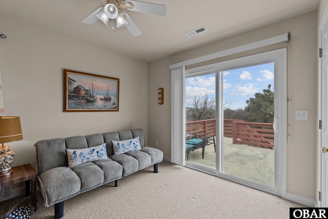 living area with visible vents, ceiling fan, light carpet, and baseboards