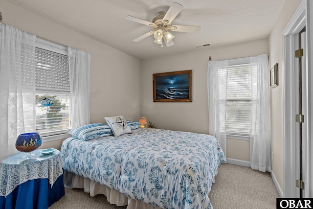 bedroom featuring carpet floors, baseboards, multiple windows, and visible vents