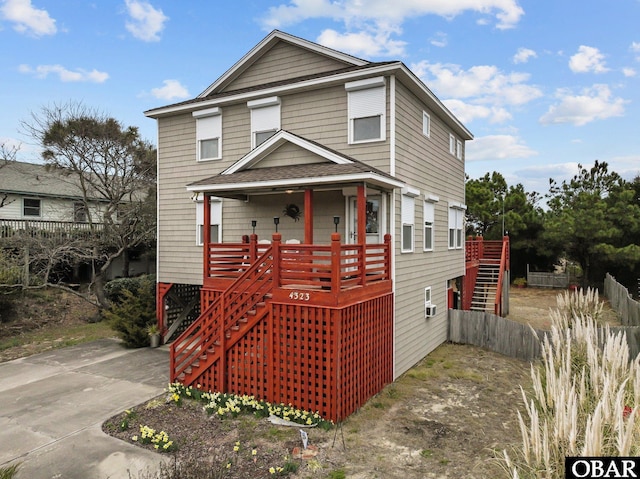 view of front of house with roof with shingles, fence, and stairway