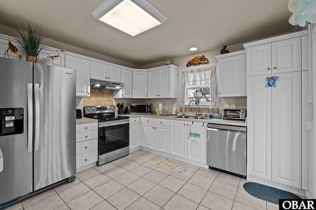 kitchen with light countertops, appliances with stainless steel finishes, a sink, and under cabinet range hood