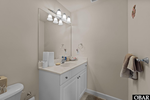 half bathroom with vanity, toilet, and baseboards