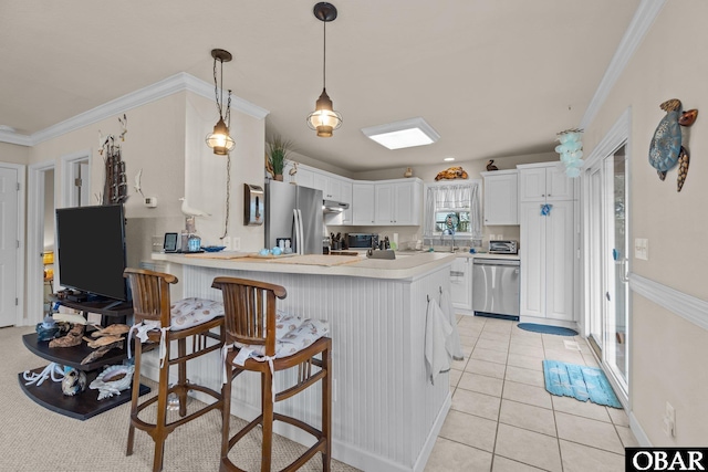 kitchen featuring stainless steel appliances, a peninsula, light countertops, and white cabinets