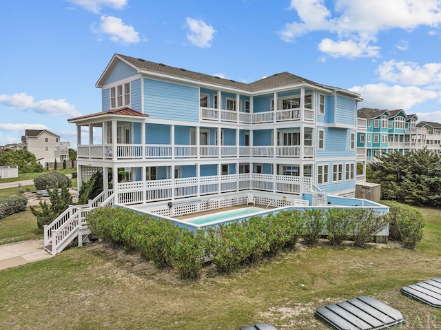 rear view of house featuring a yard, stairway, and a swimming pool