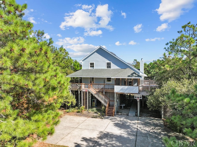 beach home with a chimney, a porch, stairway, and a shingled roof