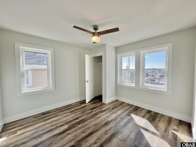 unfurnished bedroom with a ceiling fan, a closet, baseboards, and dark wood-type flooring