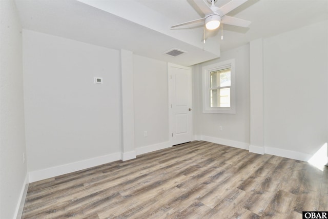 unfurnished room with visible vents, ceiling fan, baseboards, and wood finished floors