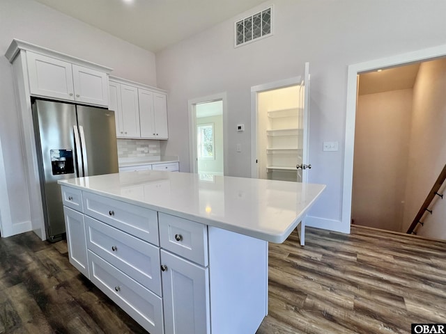 kitchen with visible vents, white cabinets, light countertops, a center island, and stainless steel fridge