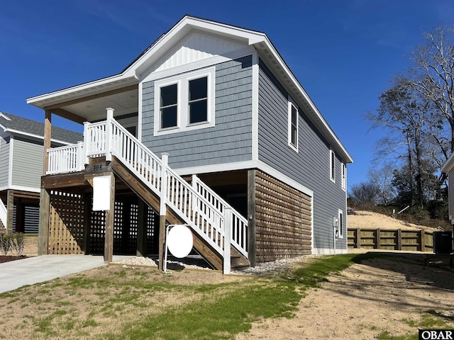 exterior space featuring fence, stairway, board and batten siding, and concrete driveway