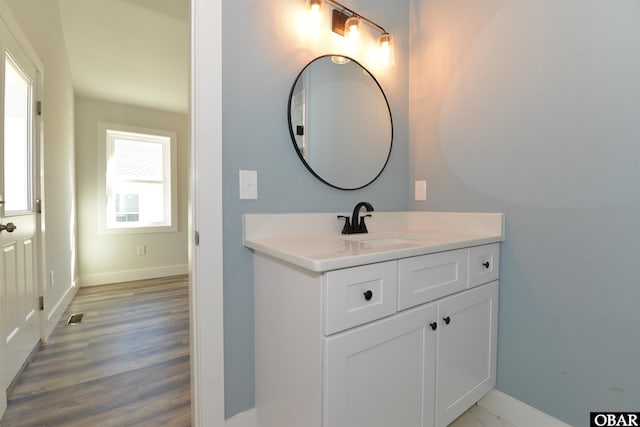 bathroom with visible vents, vanity, baseboards, and wood finished floors