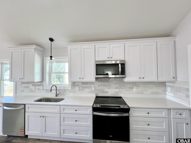 kitchen featuring stainless steel appliances, light countertops, a sink, and white cabinetry