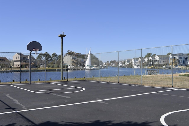 view of sport court with community basketball court, a water view, and fence