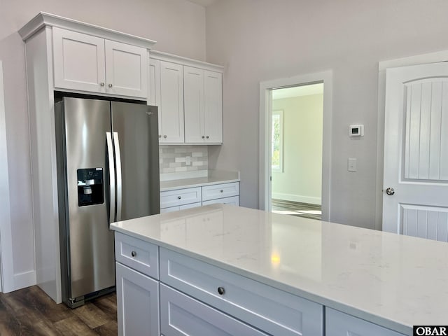 kitchen featuring tasteful backsplash, stainless steel fridge, light stone counters, dark wood-type flooring, and white cabinetry