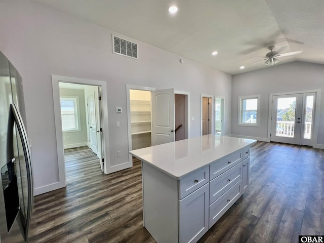 kitchen with visible vents, dark wood-type flooring, a center island, light countertops, and stainless steel refrigerator with ice dispenser