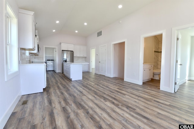 kitchen featuring visible vents, white cabinets, open floor plan, a center island, and light countertops