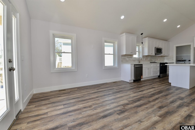 kitchen featuring stainless steel appliances, light countertops, hanging light fixtures, and white cabinetry