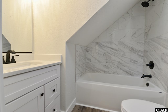 bathroom featuring lofted ceiling, toilet, wood finished floors, vanity, and  shower combination