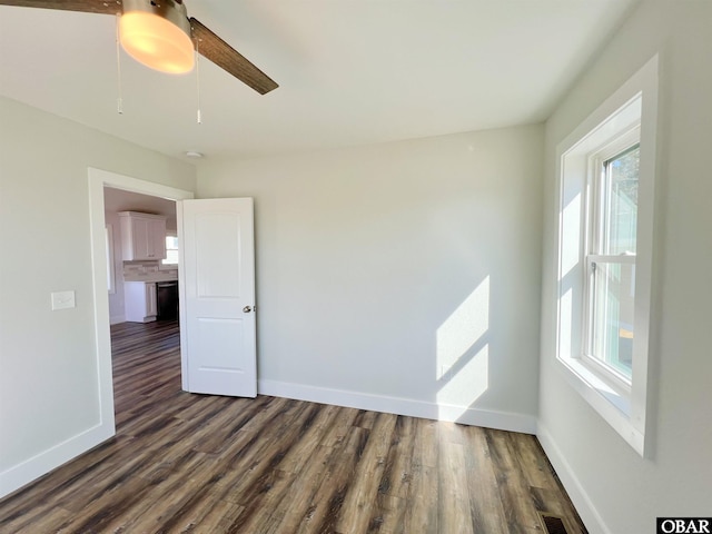 spare room featuring baseboards and dark wood finished floors