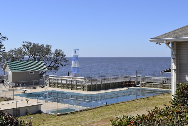 view of swimming pool with a water view, a diving board, and a fenced in pool