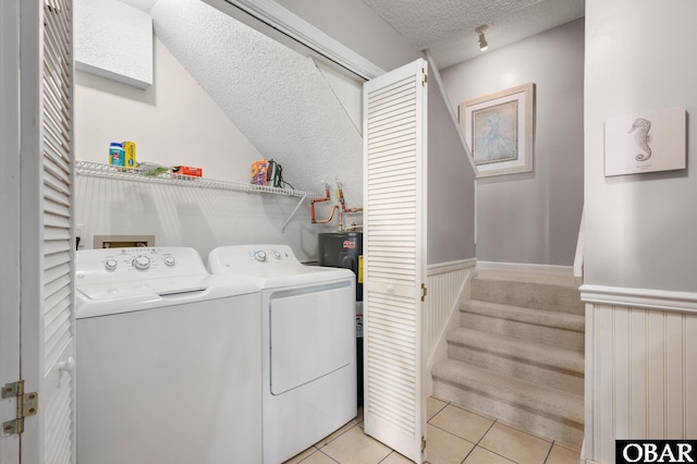 laundry room with laundry area, light tile patterned floors, wainscoting, a textured ceiling, and separate washer and dryer