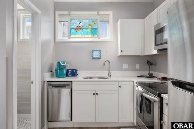 kitchen with white cabinets, appliances with stainless steel finishes, light countertops, and a sink