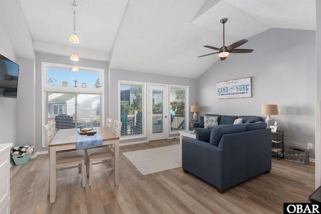 living area featuring a wealth of natural light, a ceiling fan, baseboards, and wood finished floors