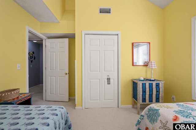 bedroom with light carpet, a closet, visible vents, and baseboards