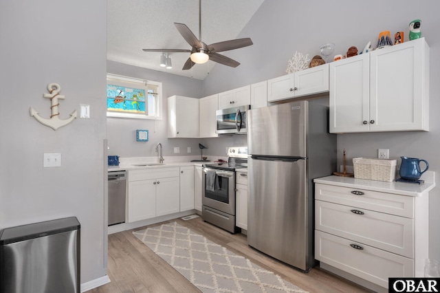 kitchen featuring vaulted ceiling, light countertops, appliances with stainless steel finishes, and white cabinetry