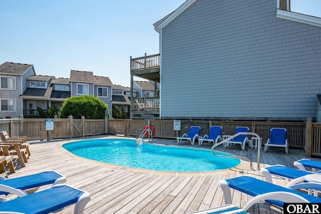 pool with a residential view, fence, and a deck