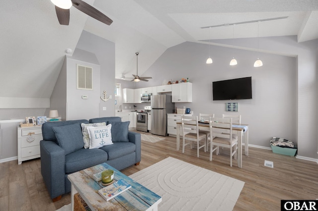 living room with lofted ceiling, visible vents, light wood-style floors, ceiling fan, and baseboards