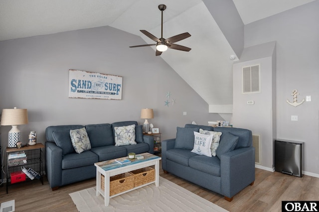 living room with a ceiling fan, visible vents, vaulted ceiling, and wood finished floors