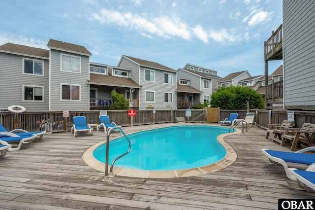 community pool featuring a residential view, fence, and a wooden deck