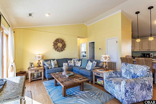 living area featuring a textured ceiling, visible vents, vaulted ceiling, dark wood finished floors, and crown molding