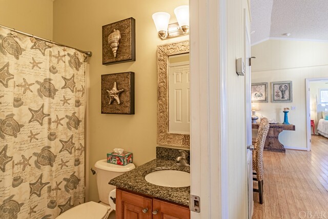 ensuite bathroom featuring toilet, vaulted ceiling, a textured ceiling, vanity, and wood finished floors