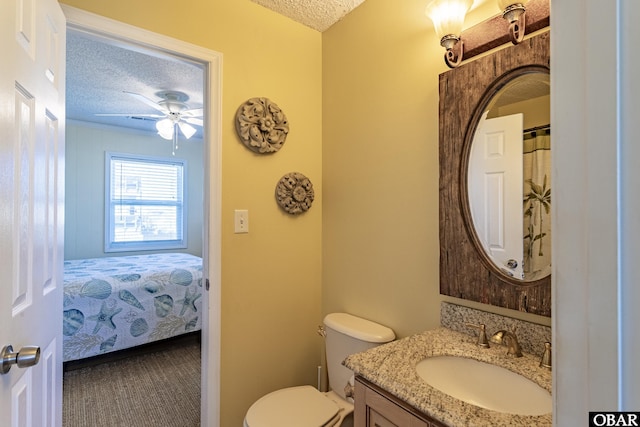 ensuite bathroom with a textured ceiling, ceiling fan, toilet, vanity, and ensuite bath