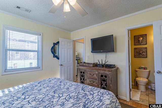 bedroom featuring a textured ceiling, ensuite bath, visible vents, and crown molding