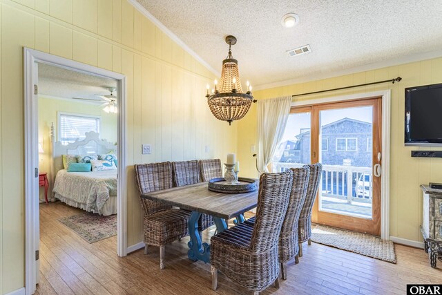 dining area featuring a textured ceiling, visible vents, crown molding, and wood finished floors