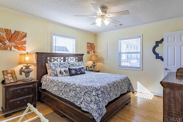 bedroom featuring a textured ceiling, ornamental molding, multiple windows, and wood finished floors