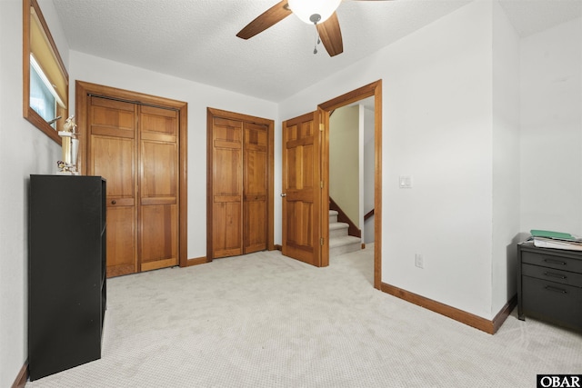 bedroom featuring a ceiling fan, baseboards, light carpet, and two closets
