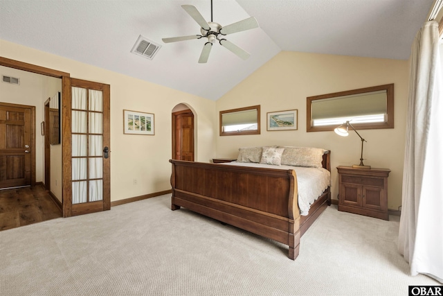 carpeted bedroom featuring arched walkways, baseboards, vaulted ceiling, and visible vents