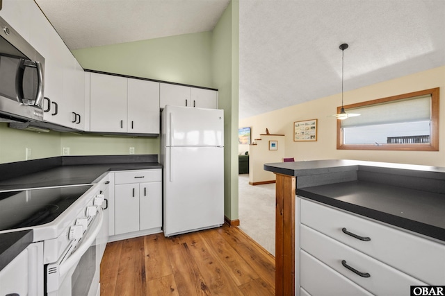 kitchen with dark countertops, lofted ceiling, light wood-style floors, white appliances, and white cabinetry