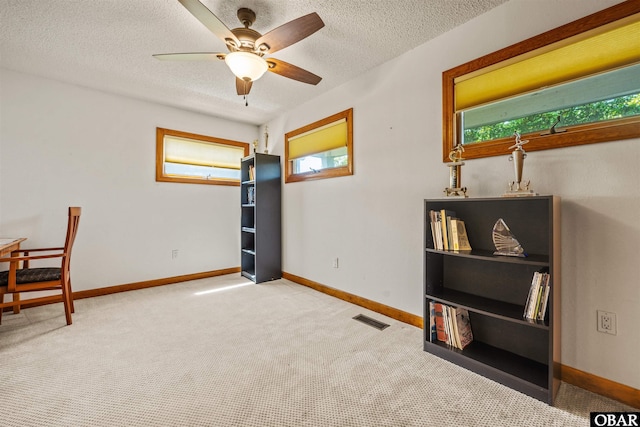 interior space featuring carpet floors, ceiling fan, baseboards, and a wealth of natural light