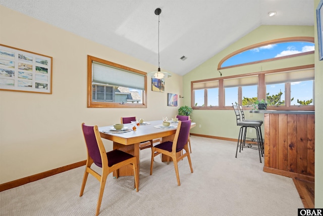 dining space featuring visible vents, vaulted ceiling, baseboards, a bar, and carpet flooring