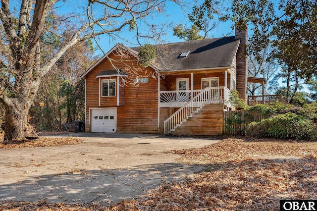 chalet / cabin featuring driveway, a chimney, an attached garage, covered porch, and stairs