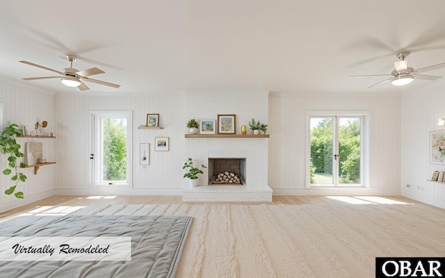 unfurnished living room with a wealth of natural light, a brick fireplace, baseboards, and wood finished floors