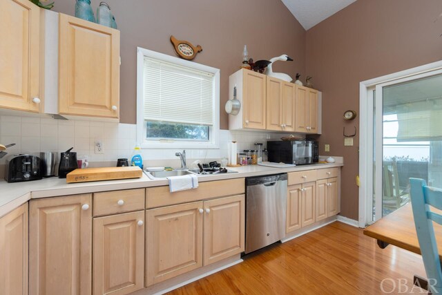 kitchen featuring decorative backsplash, dishwasher, light countertops, black microwave, and a sink