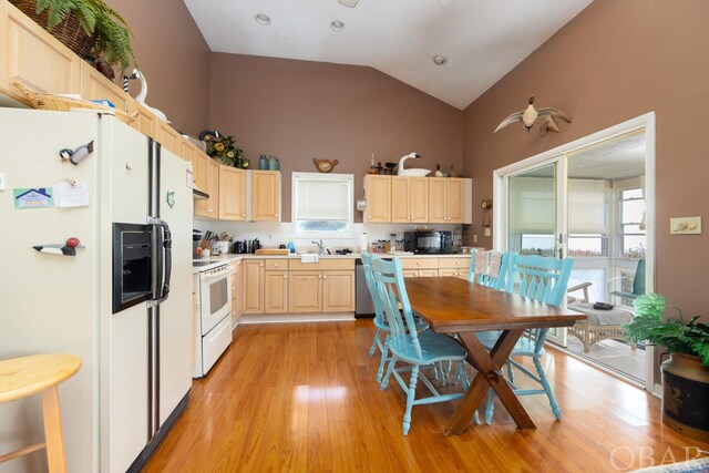 kitchen with lofted ceiling, light countertops, light wood-style flooring, light brown cabinetry, and white appliances